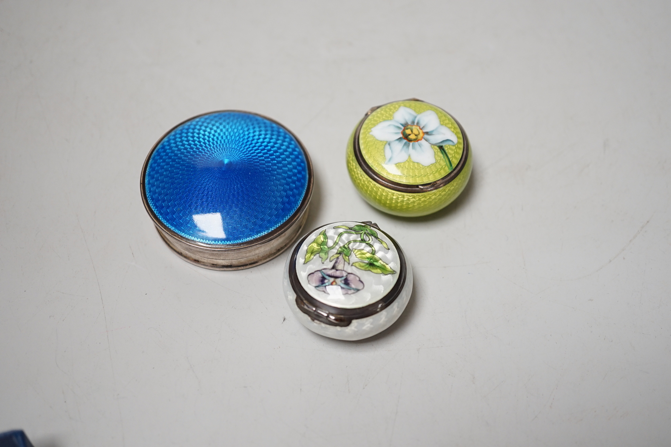 An Edwardian Art Nouveau silver and enamel pill box, import marks for London, 1901, one other 900 standard and enamel pill box and silver and enamel compact, largest 52mm.